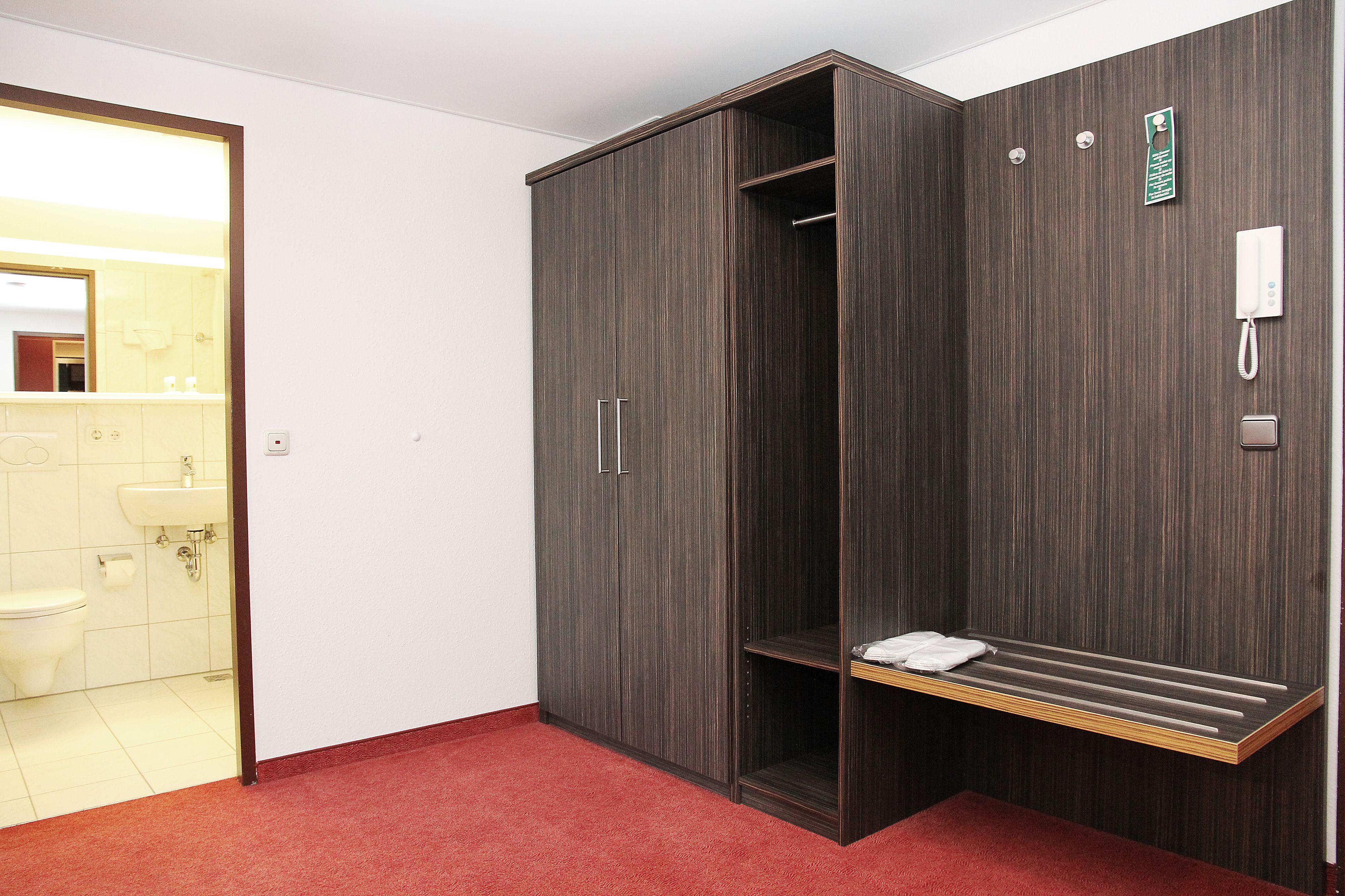 Une chambre d’hôtel équipée d’un placard, d’une douche, d’un lavabo et de toilettes.