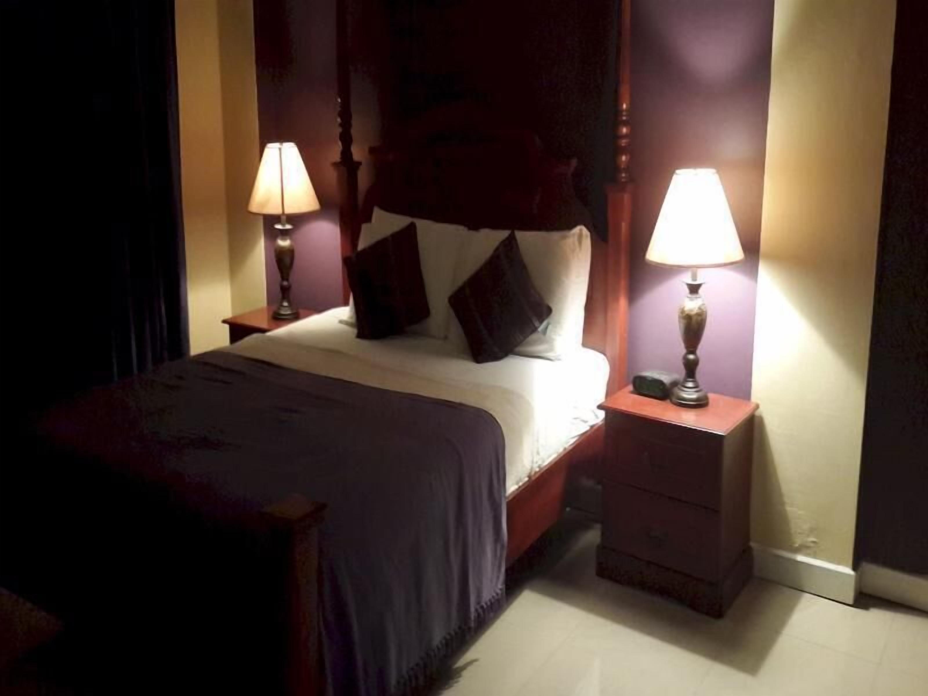 A bedroom with a bed, two bedside tables, and two lamps.