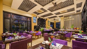 A dining area with purple upholstered chairs and tables, a ceiling fan, and a wall with the text "SILVER RIVERSIDE".