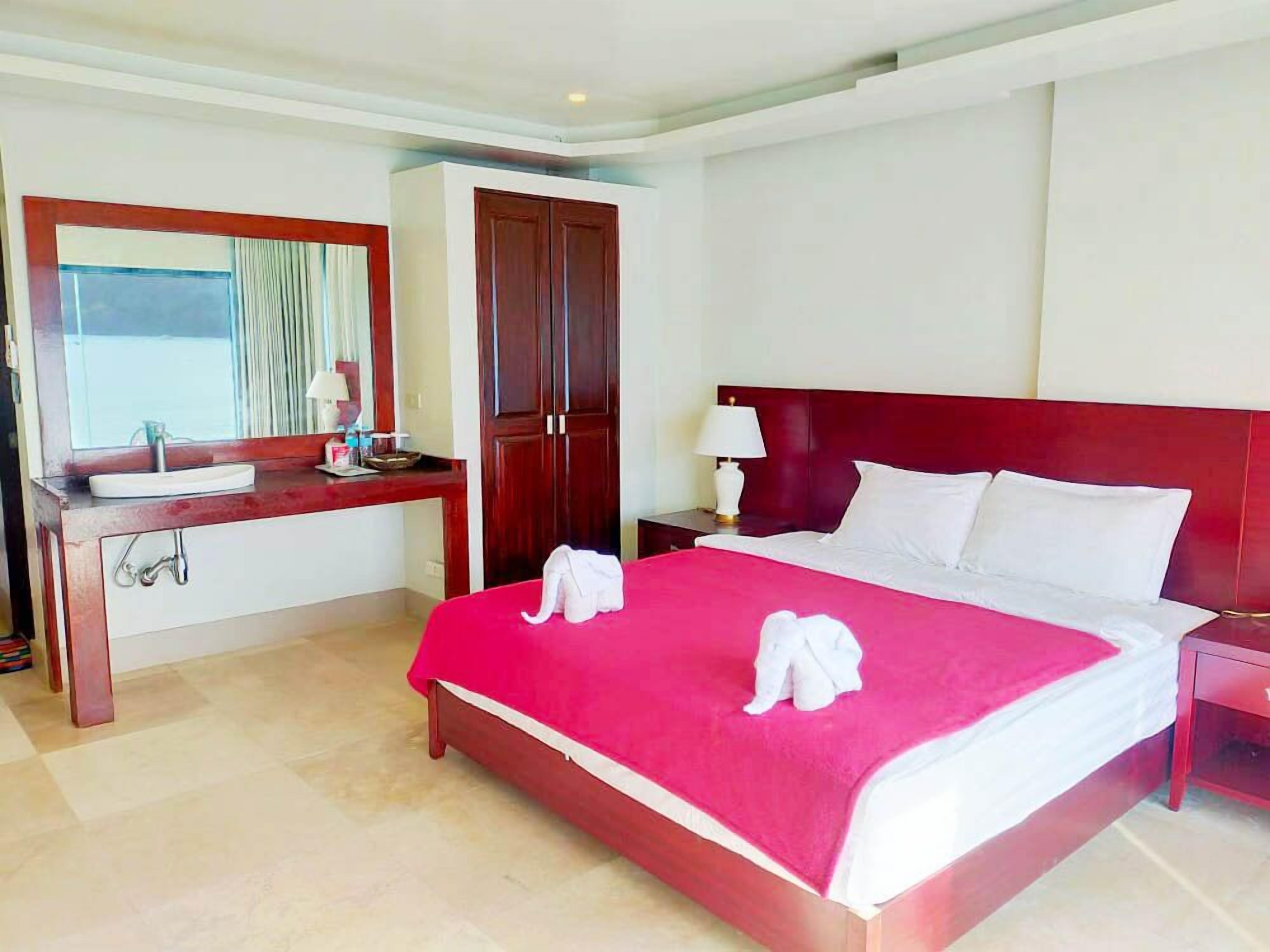 Habitación de hotel con cama, mesita de noche, escritorio con espejo y armario.
