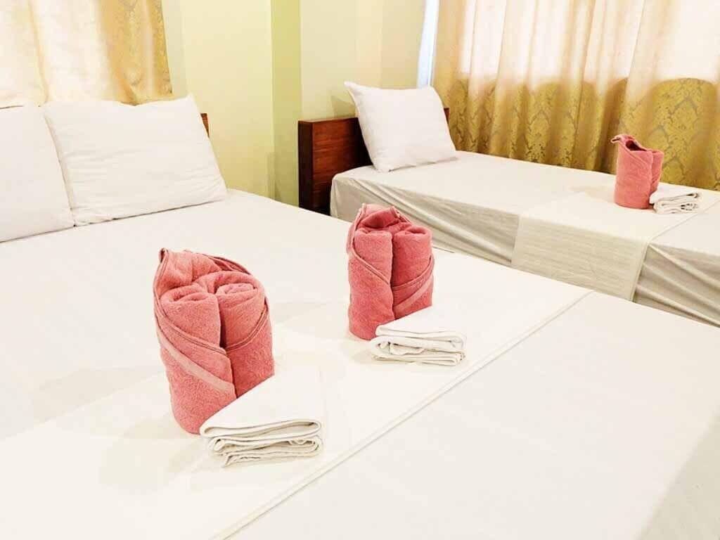 A hotel room with two beds, each with neatly folded white and pink towels.