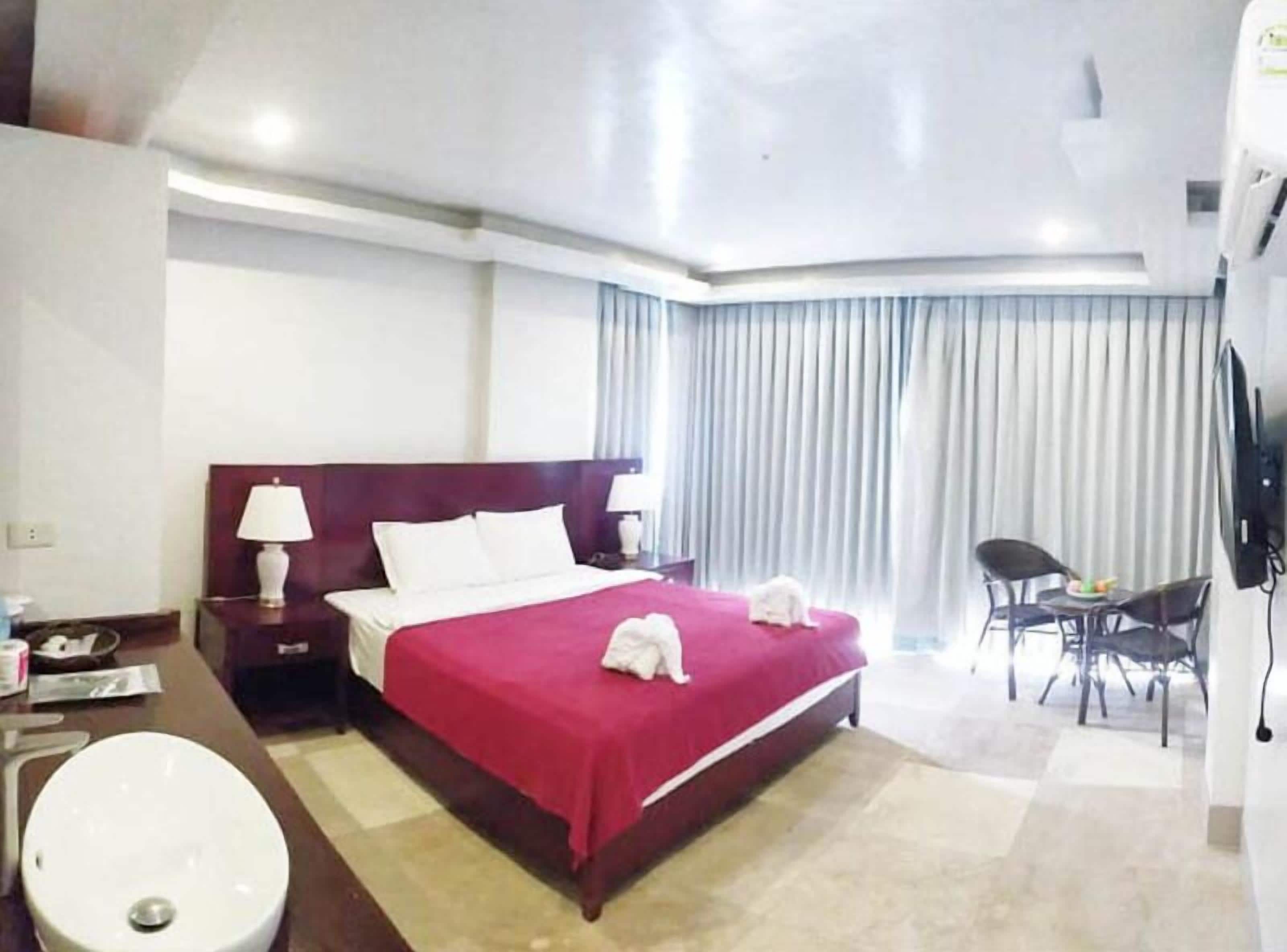 Une chambre d’hôtel avec un lit, un bureau avec une lampe, une chaise et un téléviseur.