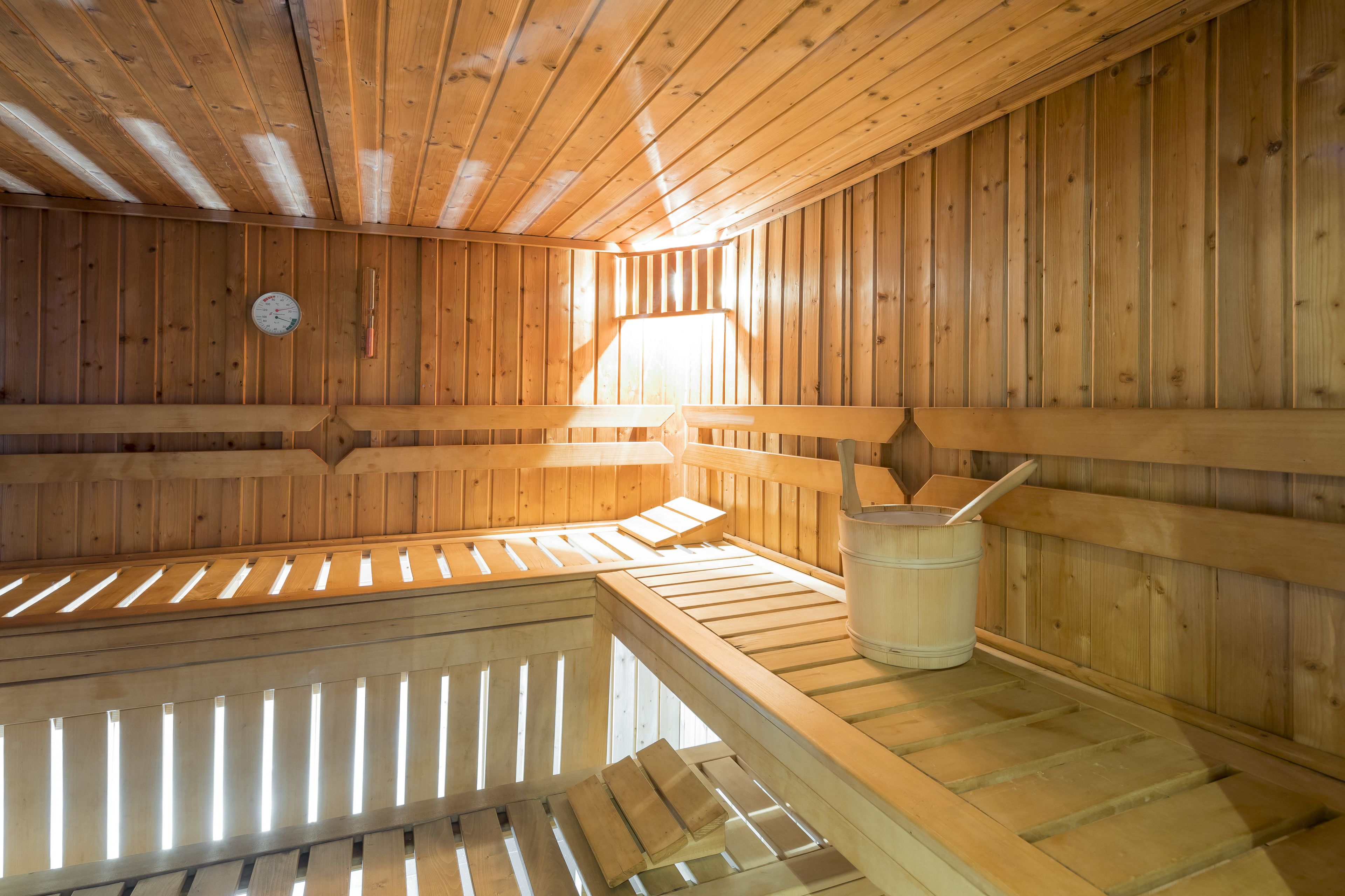 A sauna with wooden benches and a bucket.