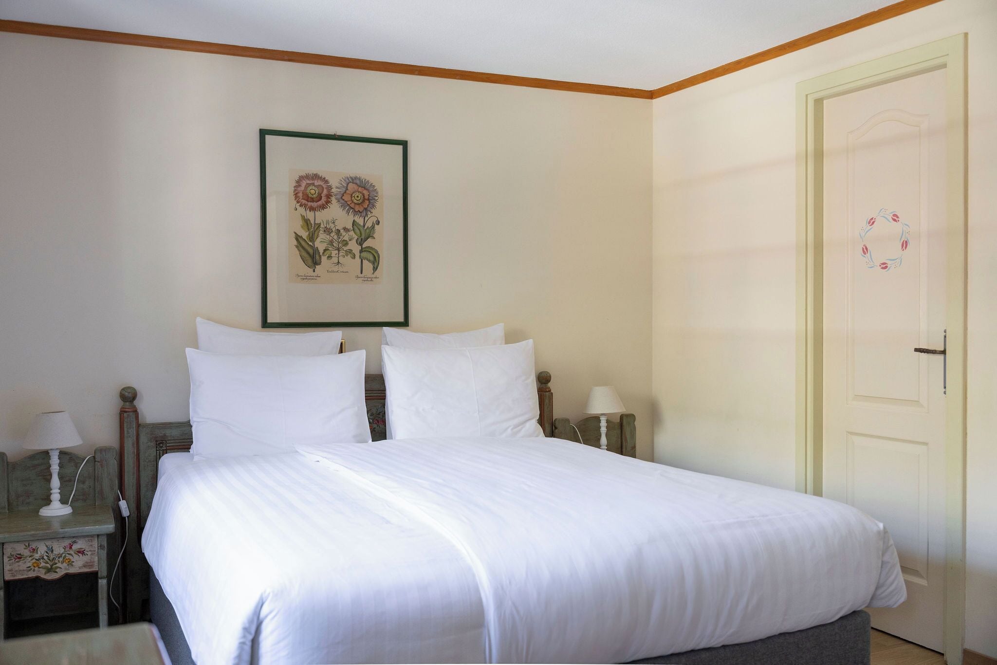 A neatly made bed with white linens in a room with a wooden headboard.