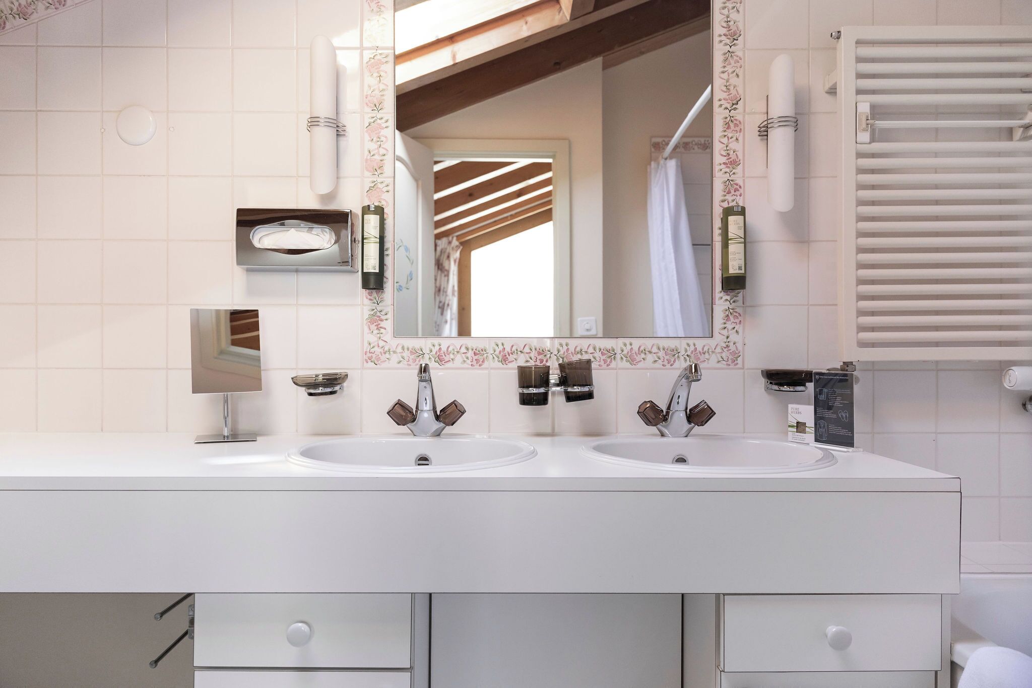 A bathroom with two sinks, a large mirror, and a towel rack.