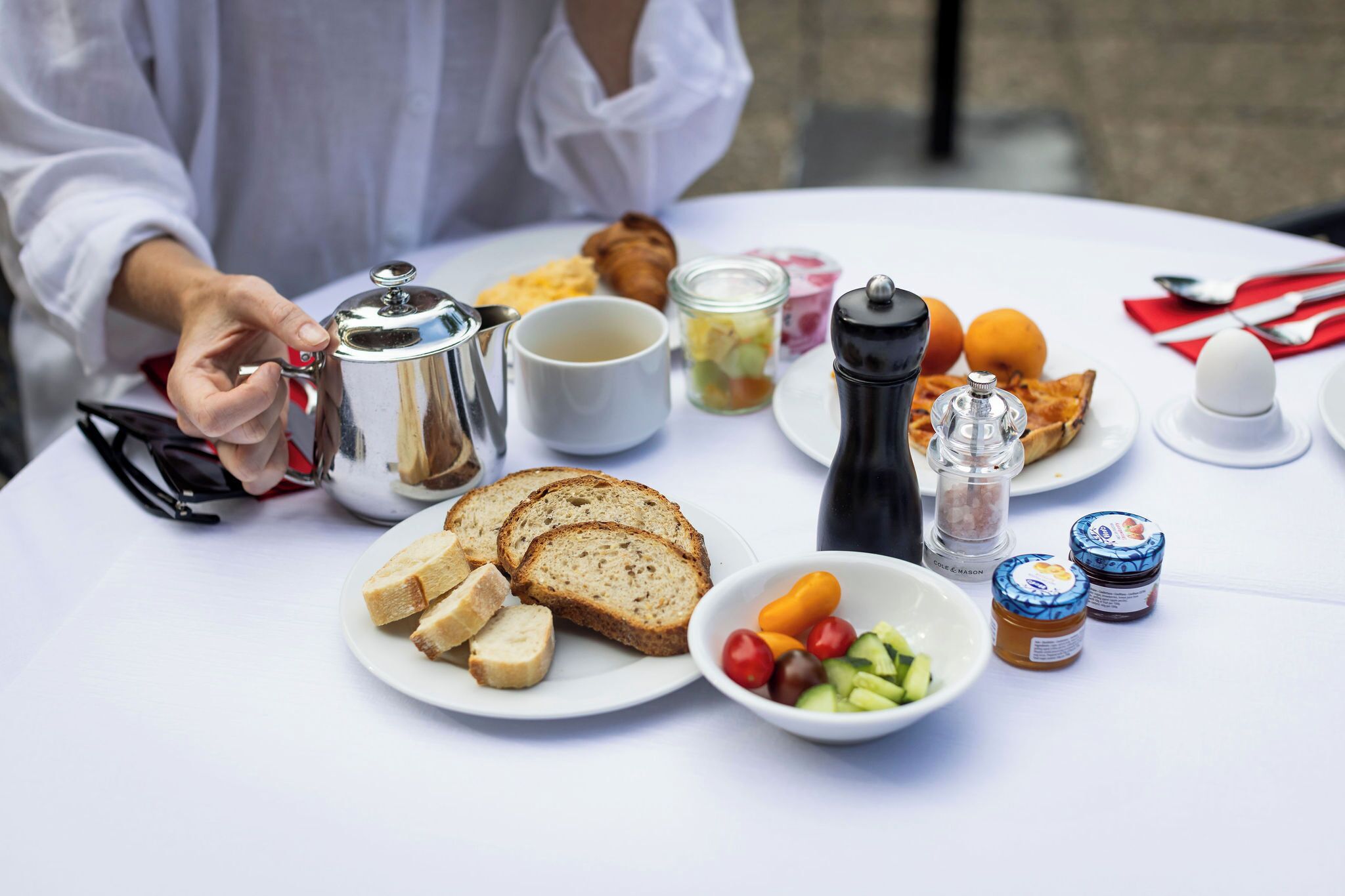 A breakfast table with various food items, a coffee pot, and condiments.