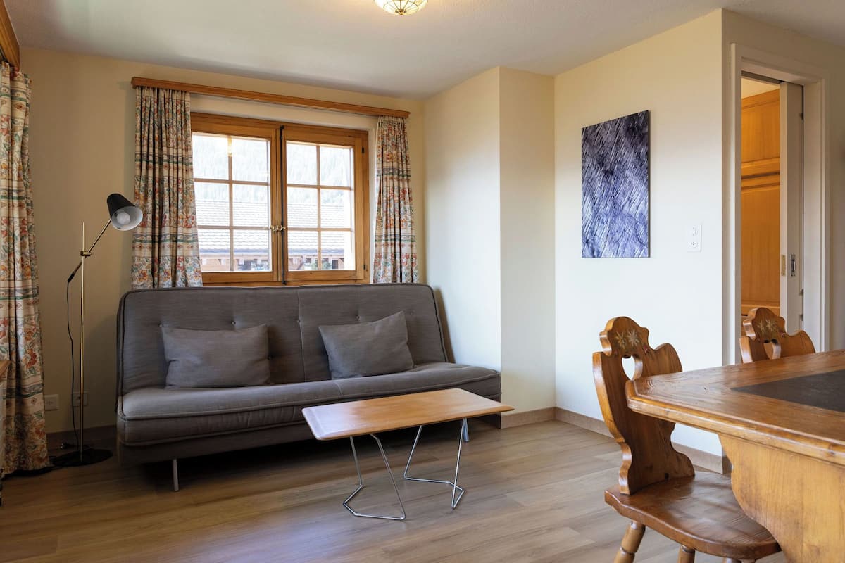 Una sala de estar con un sofá, una mesa de madera y una zona de comedor.