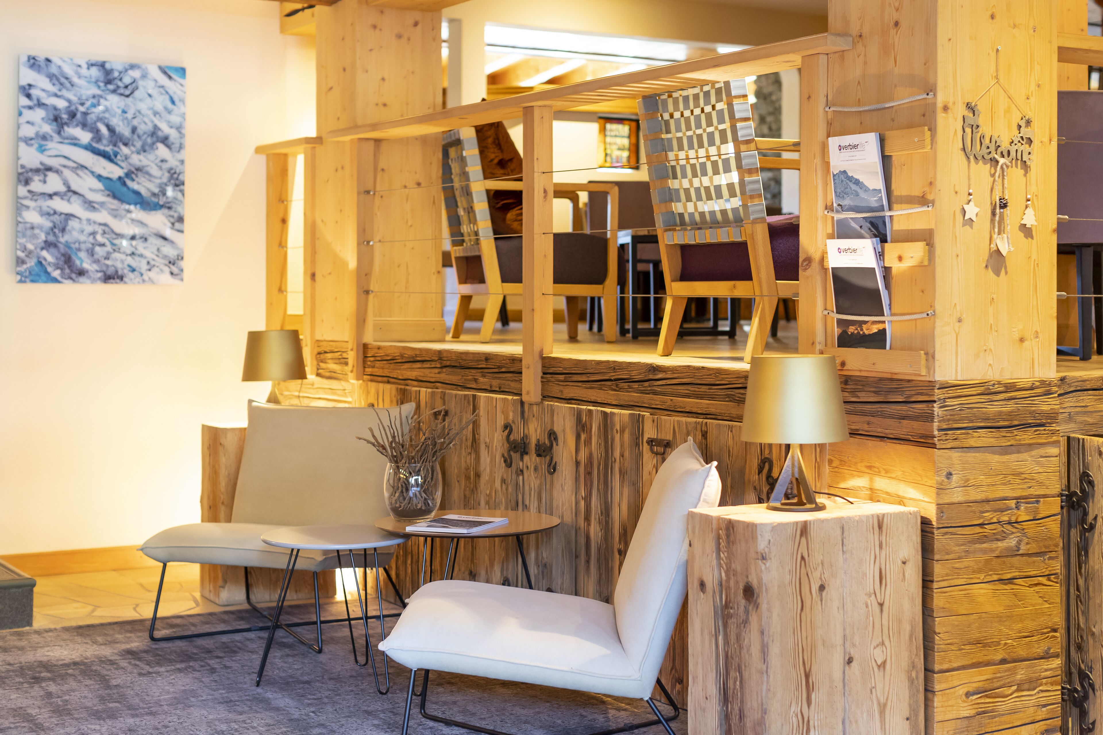 A cozy room with wooden walls, a white chair, a small table, and a lamp.