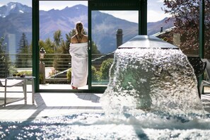 A spa area with a view of mountains, a water feature, and a person in a white towel.
