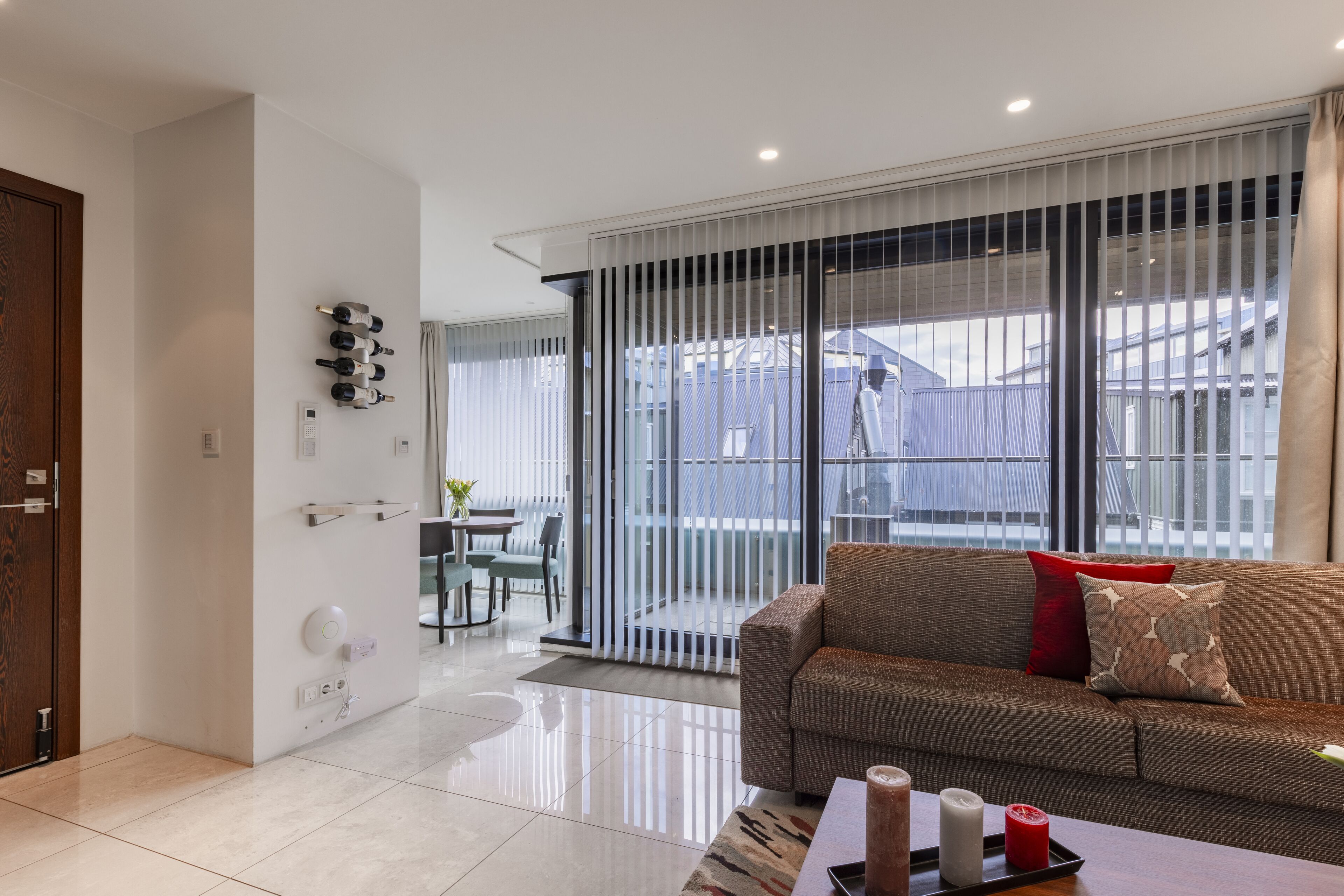 A modern living room with a sofa, a coffee table, and a sliding glass door leading to a balcony.