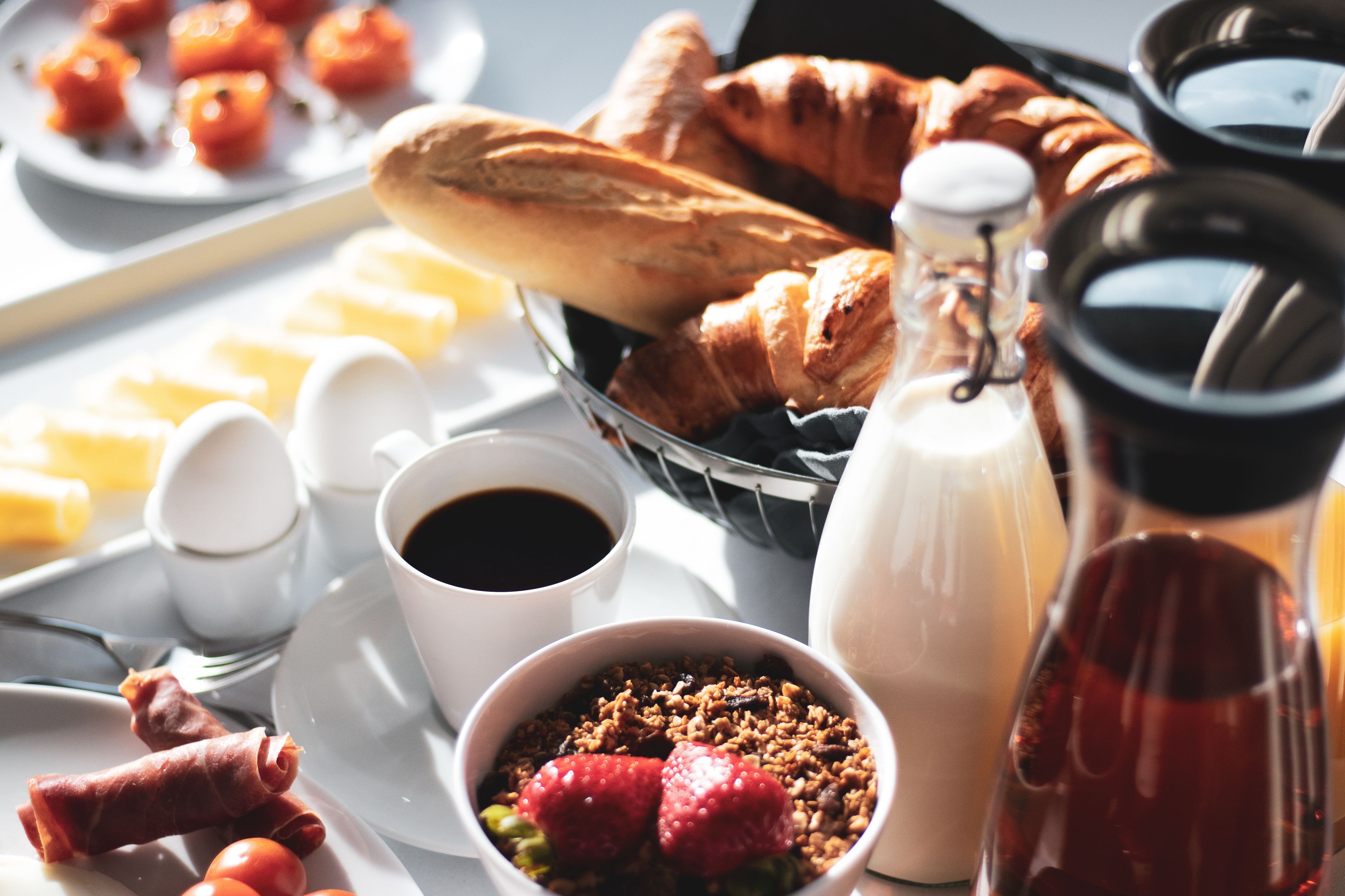Un vassoio della colazione con croissant, fragole, yogurt e caffè.