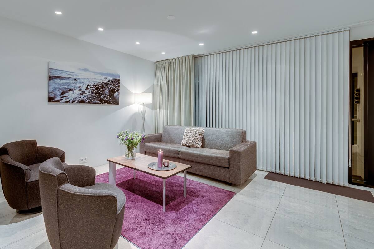 Una sala de estar moderna con un sofá, sillones, una mesa de centro y un cuadro en la pared.