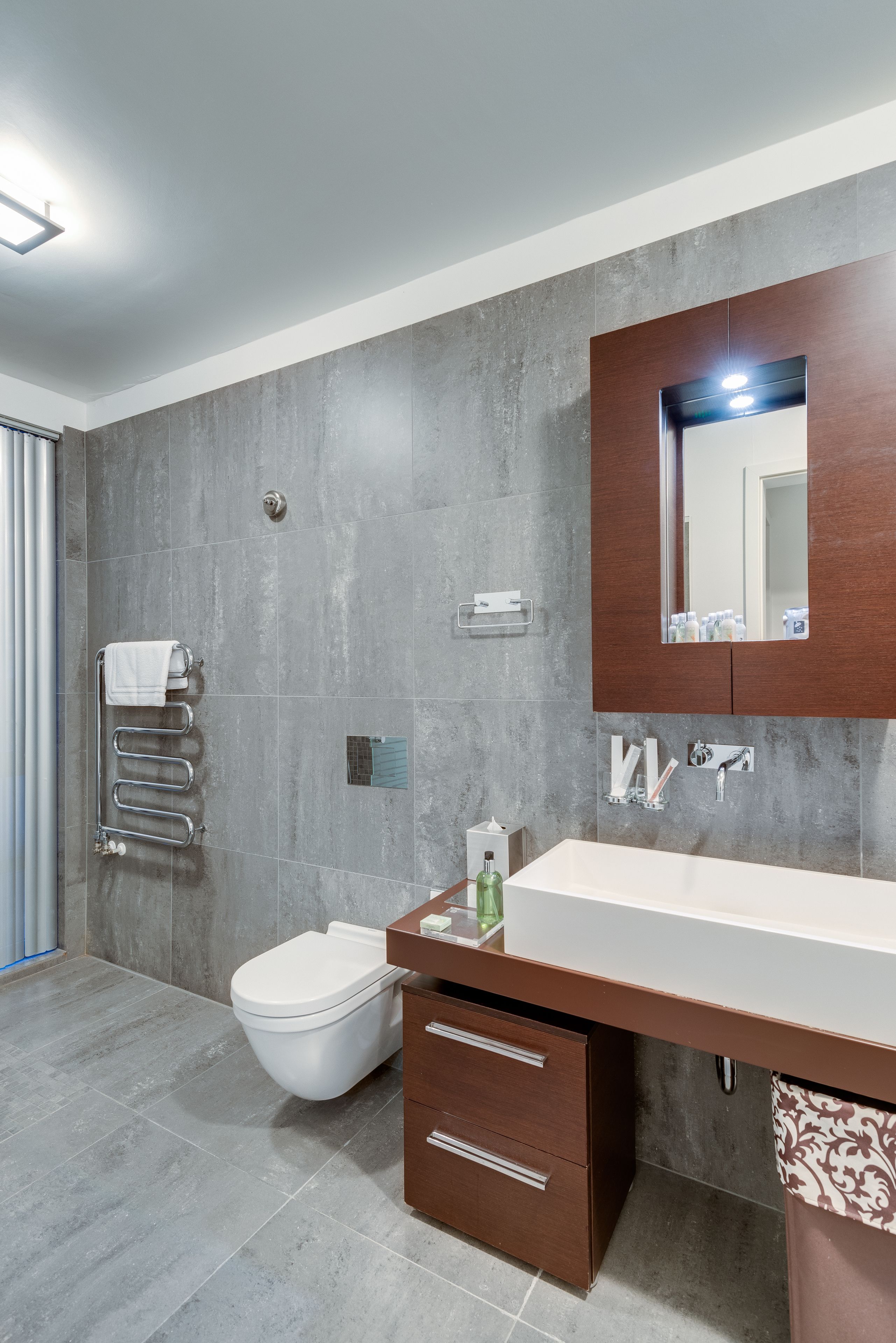 Un baño moderno con un espejo grande, un lavabo blanco y un inodoro.