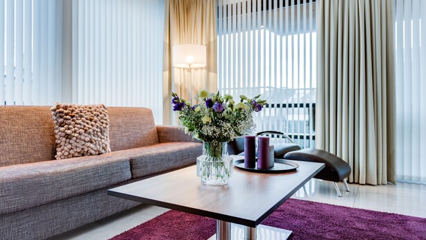 Un salon moderne avec un canapé, une table basse, un vase de fleurs et une lampe.