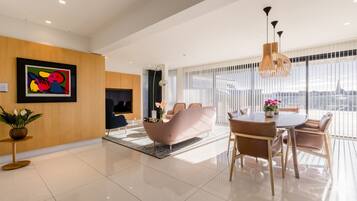 A modern living room with a sofa, a dining table, and a TV.