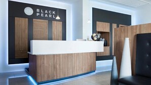 Un comptoir d’accueil moderne pour hôtel, avec un revêtement en bois et un espace détente avec des sièges en cuir noir.