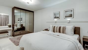 Un dormitorio moderno con una cama grande, un armario, una mesita de noche y dos cuadros colgados en la pared.