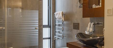 A modern bathroom with a glass-enclosed shower, a toilet, and a vanity with a black sink.