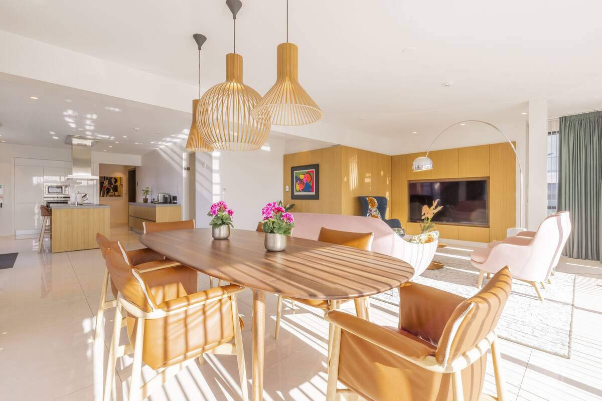 Una sala de estar moderna con una mesa de comedor de madera, sillas de cuero y un televisor de pantalla plana grande.