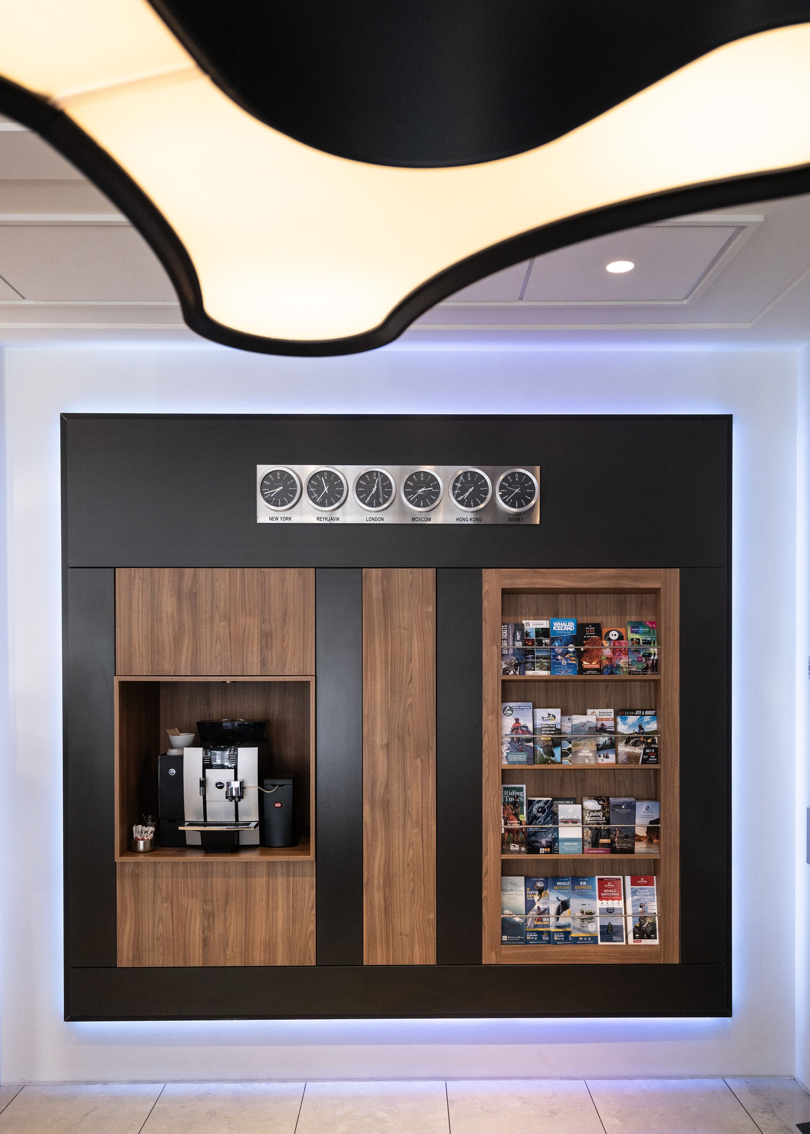Un mur avec une machine à café et une bibliothèque remplie de livres de voyage.