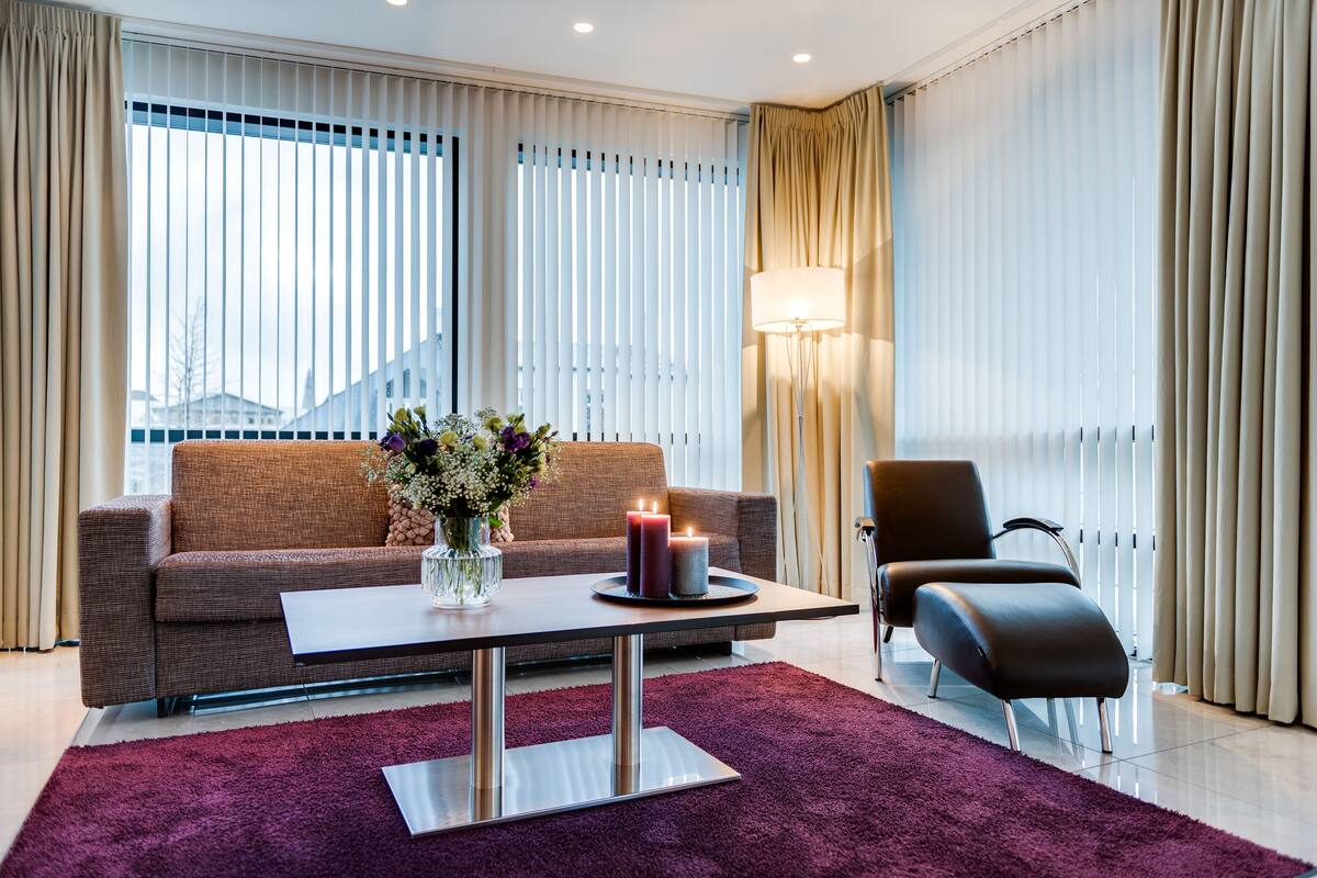 Una sala de estar moderna con un sofá, una mesa de centro con velas, una lámpara y una silla.