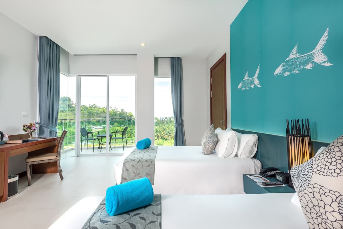 A hotel room with a balcony, a desk, and a bed with a view of the outdoors.