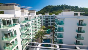 Un hôtel moderne à plusieurs étages, doté de balcons et d’une piscine centrale.