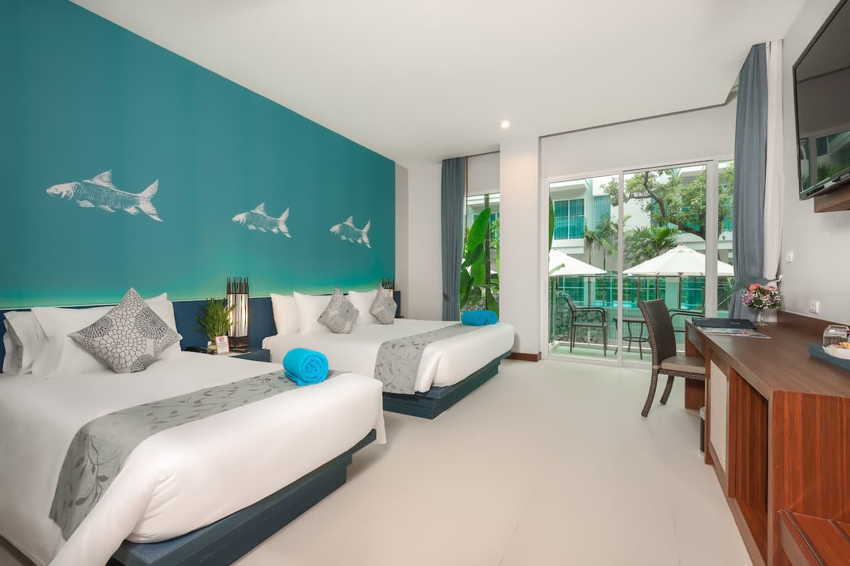 A modern hotel room with two beds, a dining area, and a balcony with outdoor seating.