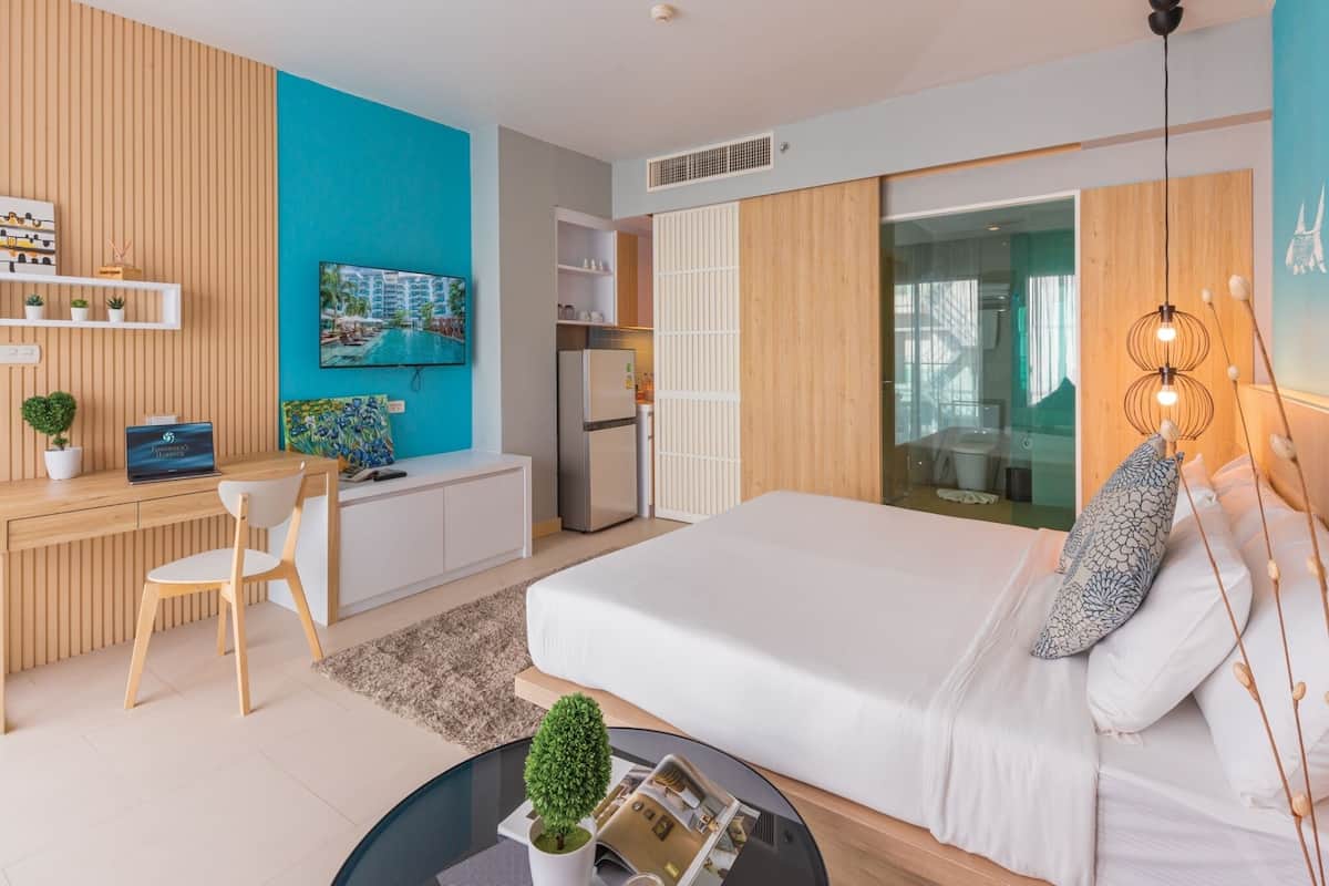 A modern hotel room with a bed, desk, chair, and a TV.