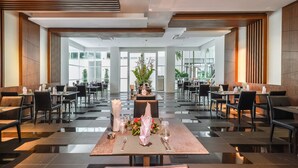 Un vaste espace dédié à la salle à manger, avec une longue table dressée pour le repas, entourée de chaises, et de grandes fenêtres offrant une vue sur l’extérieur.