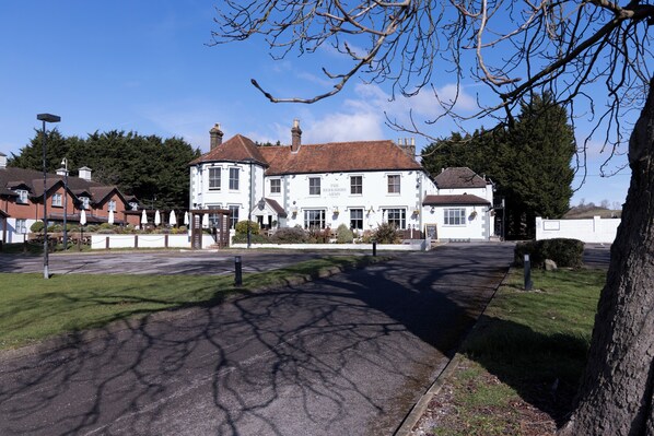 A large white building with a red roof, surrounded by a well-maintained lawn and trees.