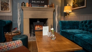 A cozy room with a fireplace, a sign above it, a table with a vase, and two sofas. - Berkshire Arms by Chef and Brewer Collection (Reading)