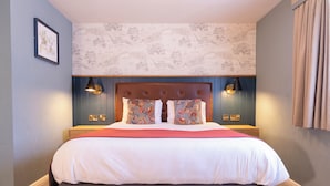 A neatly made bed with patterned pillows, a headboard, and bedside lamps. - Berkshire Arms by Chef and Brewer Collection (Reading)