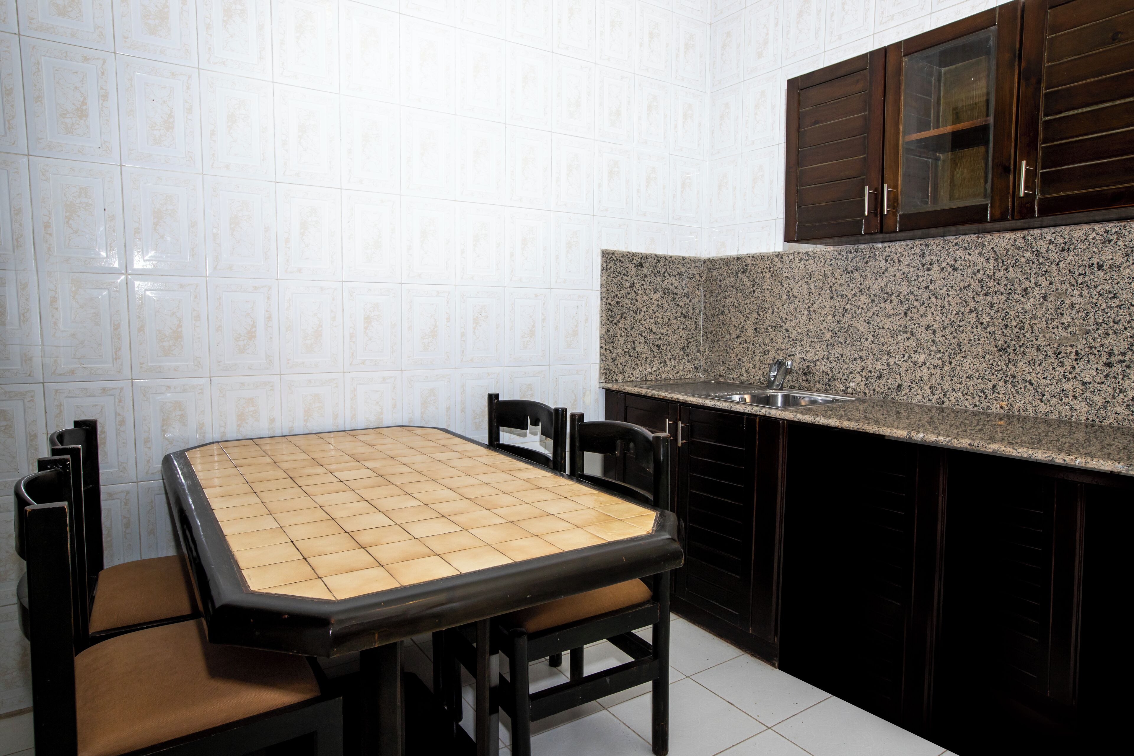 Una cocina con salpicadero de azulejos, encimera de granito y armarios de madera oscura.