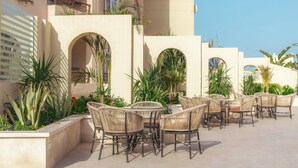 Un patio al aire libre con mobiliario de mimbre, arcos y plantas en macetas.