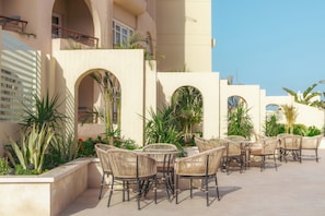 An outdoor patio with wicker furniture, archways, and potted plants.