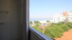 Uitzicht vanuit een raam op een strand, gebouwen en begroeiing.