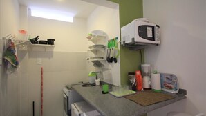 Een kleine keuken met een magnetron, bestek en een koffiezetapparaat.
