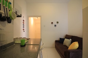 A small, well-lit room with a kitchen area, a dining table, and a couch. - GoHouse Copacabana 1005 A (Rio de Janeiro)