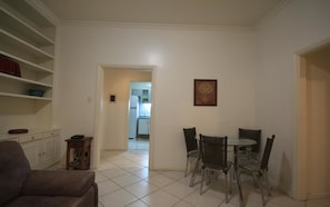 A dining area with a round table and four chairs, a sofa, and a cabinet with shelves. - Copacabana 307 (Rio de Janeiro)