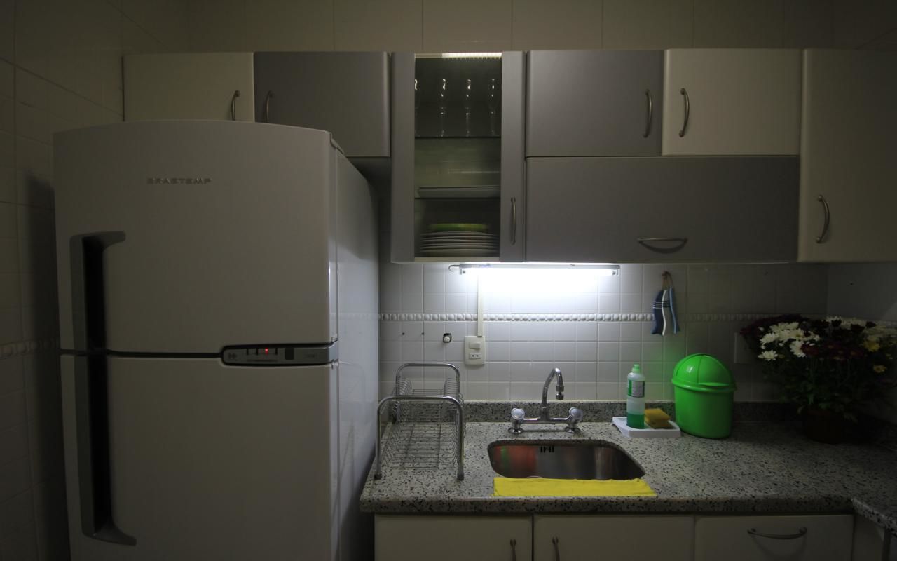Een keuken met een koelkast, spoelbak en kasten.