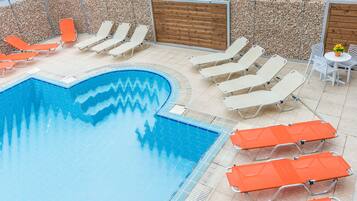 Een buitenzwembad, parasols bij het zwembad en ligstoelen