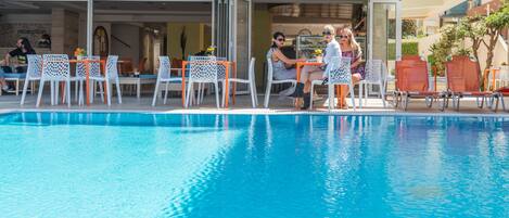 Alberca al aire libre, sombrillas en la alberca y camastros