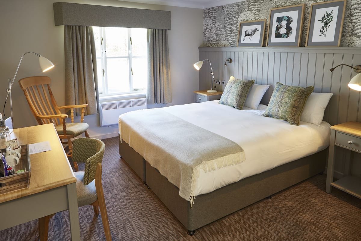 A neatly arranged bedroom with a large bed, bedside tables, a desk, and a chair.