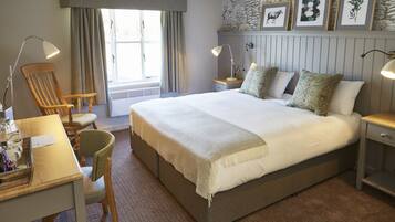A neatly arranged bedroom with a large bed, bedside tables, a desk, and a chair.