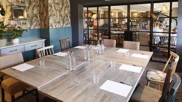 A dining area with a long wooden table set for a meeting, surrounded by chairs.