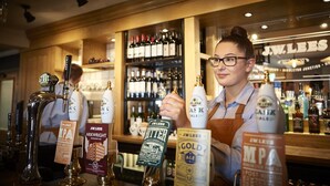 Een bar met verschillende biertaps en flessen, waaronder merken zoals J.W. Lees en Guinness.