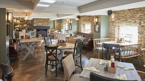 Een gezellig restaurant met houten meubels, stenen muren en een open haard.