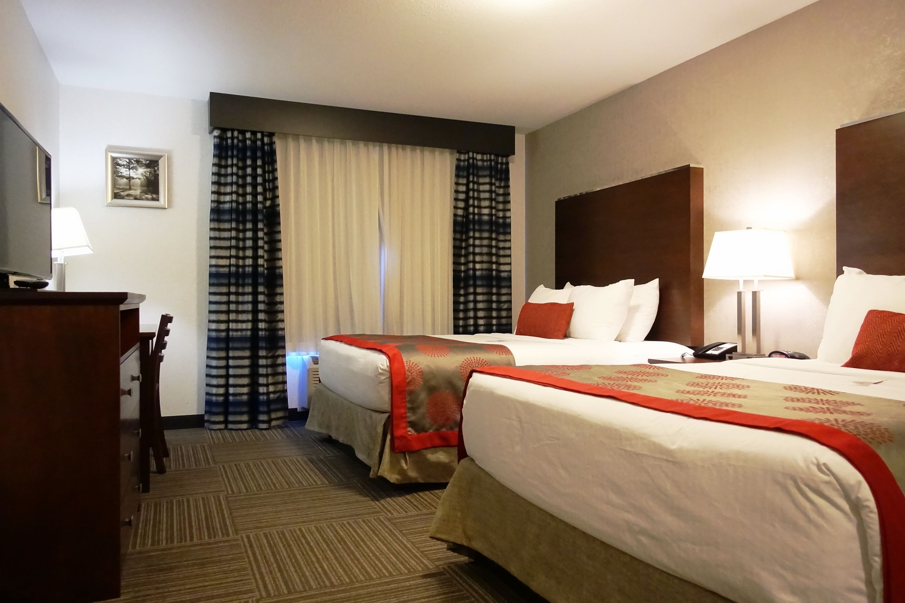 A hotel room with two beds, a desk, and a chair.