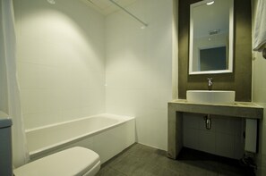 Un baño con una bañera blanca, un inodoro blanco y un lavabo con un espejo encima.